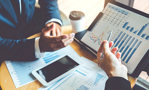 two business professionals discussing financial graphs and charts on a table with a tablet and a coffee cup showcasing insights and strategies for 8 key metrics